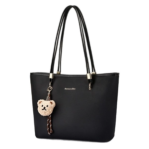 Minimalist black tote bag with gold lettering and a cute brown plush bear charm accessory