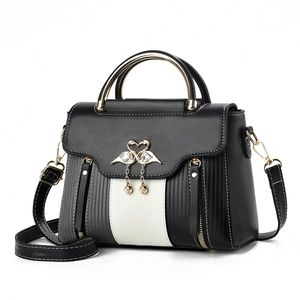 Close-up of golden swan pendant with tassel on tricolor PU leather handbag