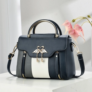Detail of blue-grey striped leather handbag with pearl swan lock and gold metal handle