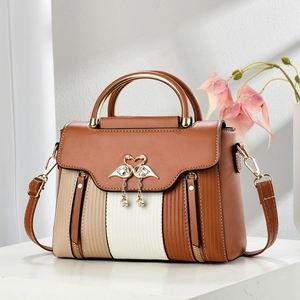 Detail of multi-color paneled crossbody bag with swan metal clasp and pearl tassel charm