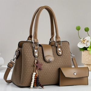 Detail of tan brown handbag set featuring woven texture and silver M buckle hardware