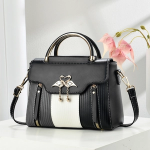 Detailed shot of golden swan buckle with rhinestone tassels on a tricolor square handbag