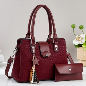 Close-up of deep red tote bag with woven texture, silver M logo and star charm