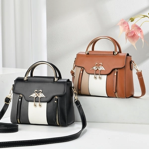 Detailed view of color-block leather bag with swan pendant and gold ring handle