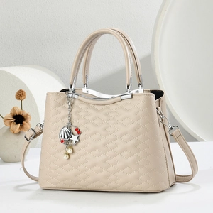 Beige quilted leather tote bag with metal frame handle and decorative shell charms
