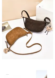 Detail of vintage suede half-moon bags in brown and caramel with plush bear charms