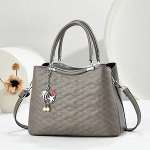 Detail of grey quilted handbag featuring decorative starfish and pearl charms with strap
