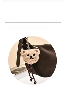 Plush bear pendant charm with lamb wool texture hanging on a brown leather shoulder bag