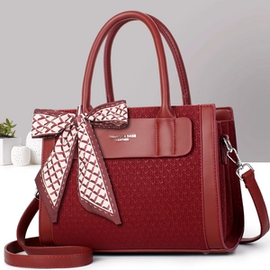 Burgundy woven tote bag with top handle and floral scarf on a minimalist studio backdrop