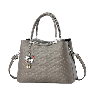 Taupe quilted leather tote bag with silver hardware and decorative charm pendant