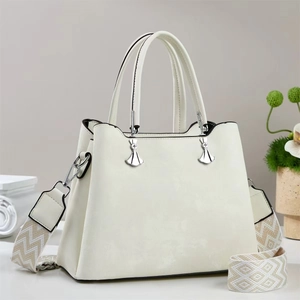 Detail der weißen Handtasche aus Leder mit Silberanhängern und gewebtem Schultergurt