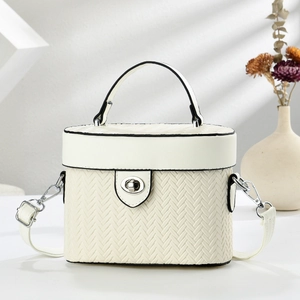 Détail de la texture tissée du sac vanity ivoire avec fermoir rotatif en métal argenté