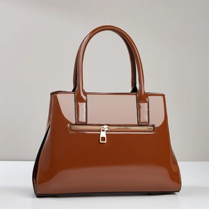 Detailed side view of a brown glossy patent leather handbag with golden hardware