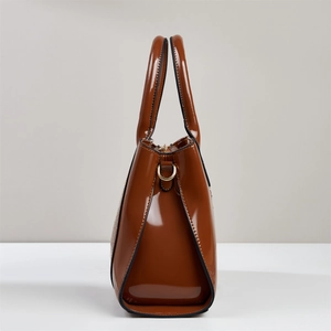 Detailed side view of brown glossy crocodile pattern handbag with metal ring hardware