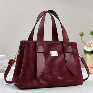 Sac à main élégant rouge foncé avec textures verticales et détails dorés sur un socle