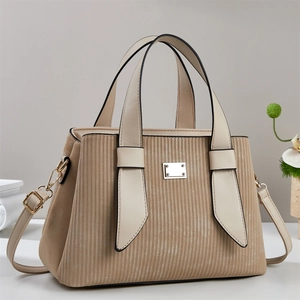 Détail de la texture velours côtelé et plaque dorée sur sac à main beige avec poignées
