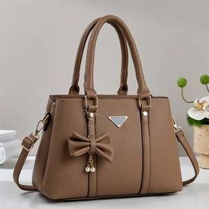 Détail du sac à main en cuir marron grainé avec pendentif perle et finitions métalliques