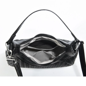 Detail view of woven black handbag showing interior herringbone lining and zipper pocket