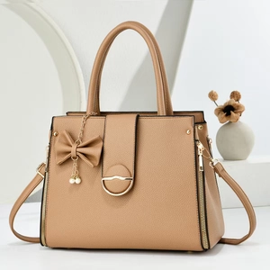 Detail of camel leather tote with gold hardware, pearl charm and lychee texture
