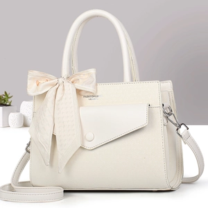 Detail of cream leather handbag with silk scarf bow and elegant textured finish