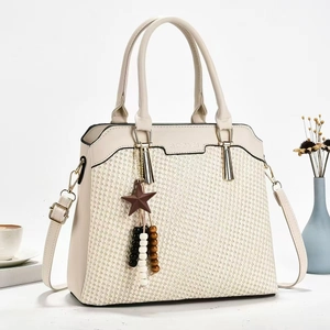 Chic cream woven handbag with star charm and shoulder strap in an elegant lifestyle setting