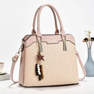 Detail of light pink woven handbag with golden star charm and adjustable shoulder strap