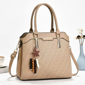 Detail of elegant beige woven handbag with star charm and beaded tassel accessory
