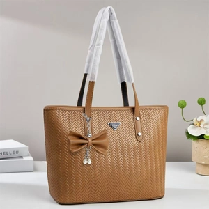 Detail of brown woven tote bag with leather bow and pearl charm ornament