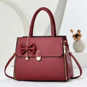 Chic burgundy satchel with lychee texture, bow pendant, and elegant pearl accents