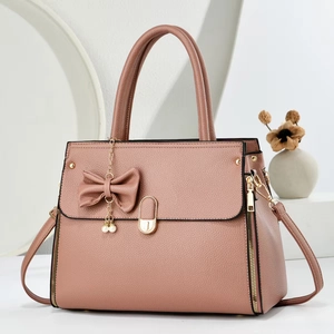 Elegant dusty pink lychee leather handbag with pearl charm and bow on white background