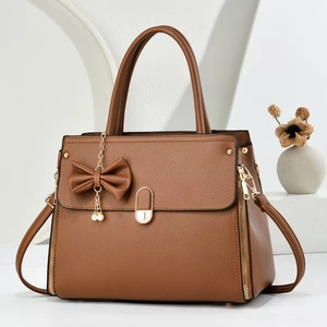 Detail of brown litchi pattern leather tote with pearl bow charm and golden hardware