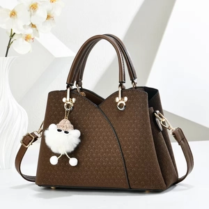 Brown leather tote bag with V-weave texture and white charm on a minimalist background