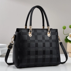 Détail du sac cabas en cuir noir à motif damier avec finitions métalliques dorées