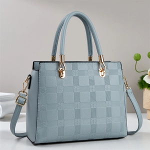 Détail d'un sac cabas bleu clair en cuir gaufré à damier avec des ferrures dorées