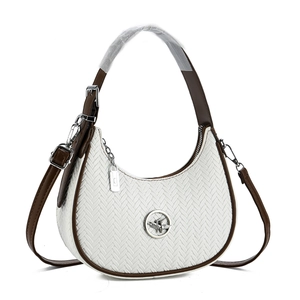 Close-up of white woven leather hobo bag with brown trim and metallic bird emblem