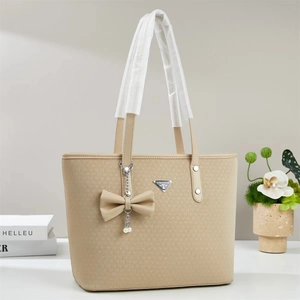 Chic beige woven tote bag for women featuring a stylish bow and pearl chain charm