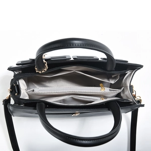 Interior view showing multiple compartments and gold zippers of black woven tote bag