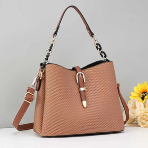 Detail view of brown woven texture and gold chain strap on a stylish crossbody bag