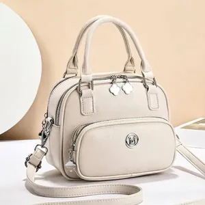 Macro shot of beige lychee texture PU leather handbag with gold clover zipper pulls
