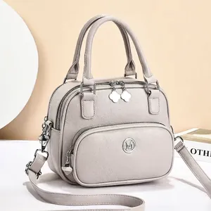Detail of light gray lychee grain leather handbag with clover metal zipper pull and M logo
