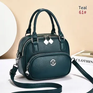 Detailed macro of blue-green lychee texture leather handbag with silver M logo and clover charm