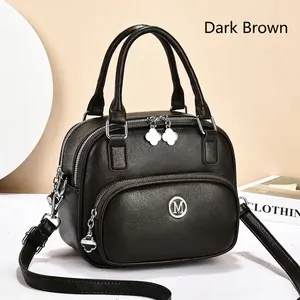 Detail of dark brown lychee leather handbag with silver M logo and clover zipper pull