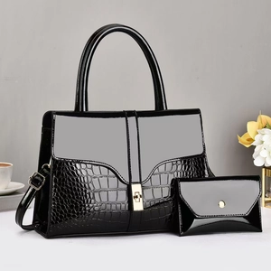 Detail of glossy black faux crocodile skin handbag and matching pouch with gold lock