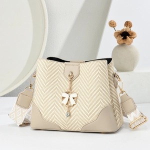 Detailed view of beige woven bucket bag with leather trim and jewel bow charm