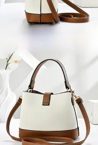 Detail of two-tone bucket bag featuring beige textured leather and brown straps with gold hardware
