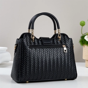 Detail of black woven texture handbag featuring gold hardware and a back zipper pocket