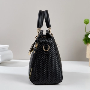 Detail of black woven texture leather handbag with elegant gold hardware accents
