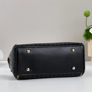 Detail of black woven bag bottom with golden protective studs and fine leather texture