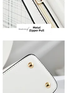 Close-up of golden hardware zipper pull and protective rivets on white leather bag