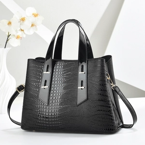 Detailed close-up of glossy black crocodile embossed handbag with gold metal hardware